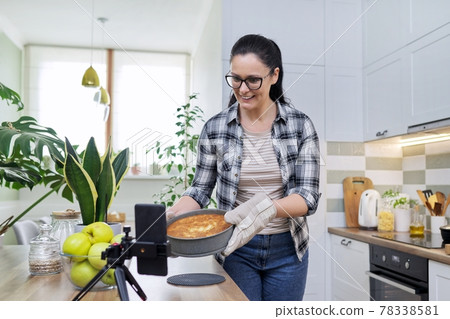 Food blog, woman cooking apple pie at home, recording recipe on smartphone 78338581