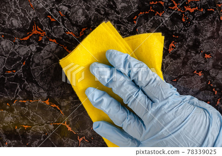 Close-up of a female hand cleaning a dark floor tile with a pattern. Close-up of a female hand cleaning a dark floor tile with a pattern. 78339025