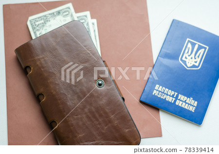 Brown leather wallet and Ukrainian passport on the table. 78339414