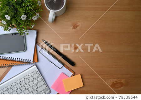 High angle view of simple workspace with smart phone, notebook, sticky note and coffee cup on wooden desk. High angle view of simple workspace with smart phone, notebook, sticky note and coffee cup on wooden desk. 78339544