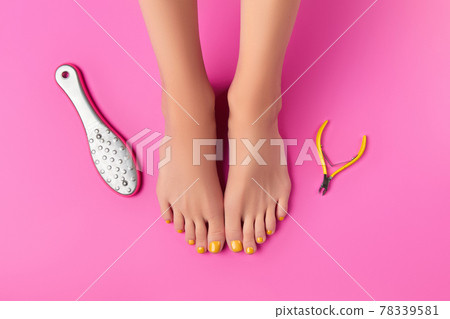 Manicure, pedicure beauty salon concept. Womans feet with clippers and foot grater on pink background Manicure, pedicure beauty salon concept. Womans feet with clippers and foot grater on pink background 78339581