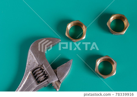 Adjustable wrench and three nuts on a green background. Adjustable wrench and three nuts on a green background. 78339916