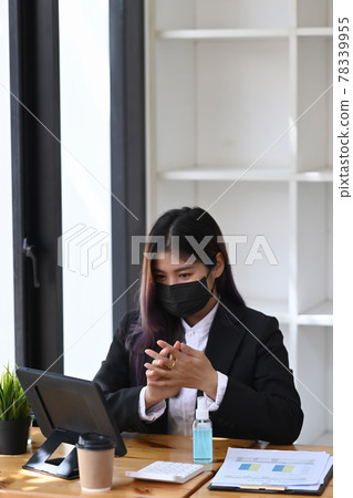 Businesswoman in protective mask using hand sanitizer gel at her office. Businesswoman in protective mask using hand sanitizer gel at her office. 78339955
