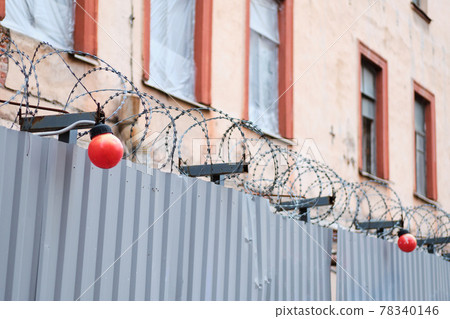 Repair the building and the fence in front of it with barbed wire. 78340146
