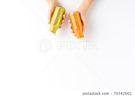 Female hands holding bottles of fruit and vegetable smoothies isolated on white background with copyspace. Top view 78342601
