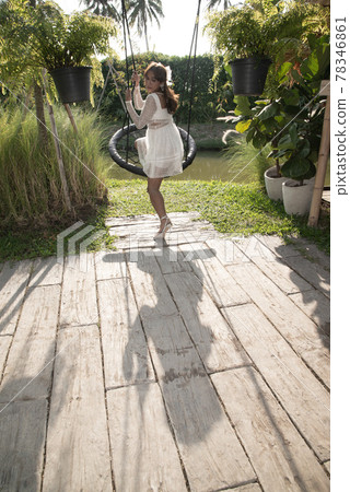 Young pretty Asian woman is swinging at a swing on the park. 78346861