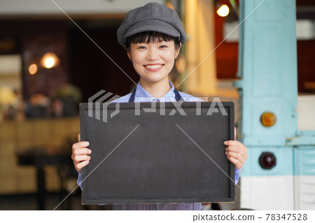 Female clerk holding a message board in front of the kitchen car 78347528