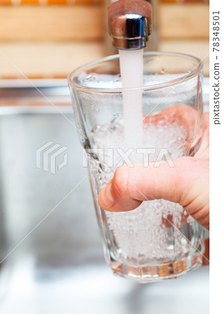 Filling up a glass with water from kitchen tap POV 78348501