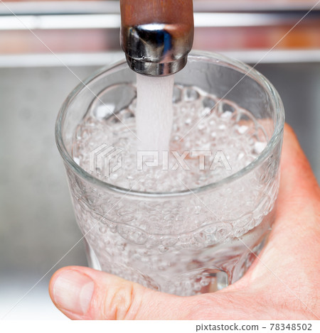 Filling up a glass with raw water from kitchen faucet 78348502