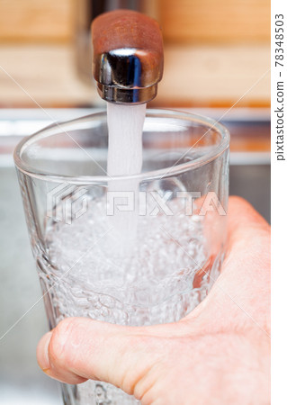 Filling up a glass with drinking water from kitchen tap 78348503