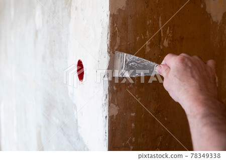 Repairing the wall - Man putting spackle on a hole in the wall 78349338