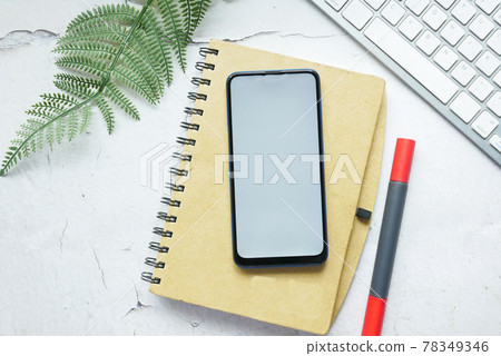 smart phone with empty screen on notepad on table smart phone with empty screen on notepad on table 78349346