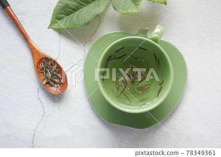 top view of green tea and herbal leaf in a small glass bowl on table  78349361