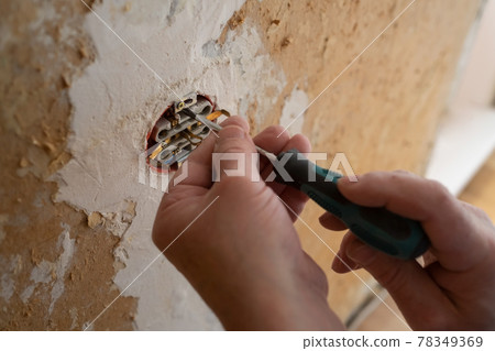 Hands of electrician installing electrical socket with new home Hands of electrician installing electrical socket with new home 78349369