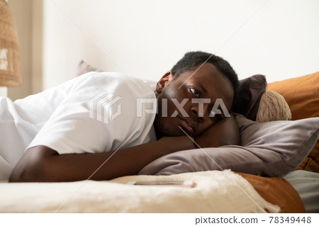 Lonely african man in bed with mobile smartphone waiting for call Lonely african man in bed with mobile smartphone waiting for call 78349448