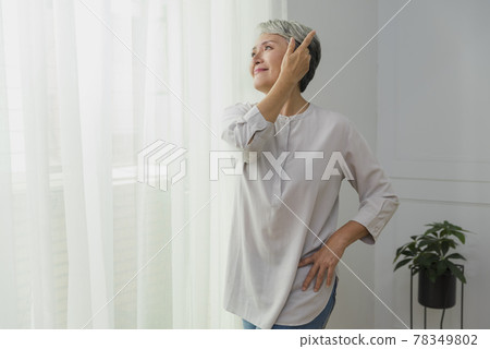 Portrait of an older woman with silver hair by a floor-to-ceiling window Portrait of an older woman with silver hair by a floor-to-ceiling window 78349802
