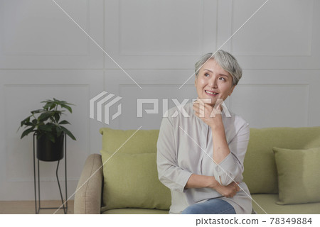 一位銀髮族年長婦女,坐在客廳的沙發上,享受悠閒自在的生活 一位銀髮族年長婦女,坐在客廳的沙發上,享受悠閒自在的生活 78349884