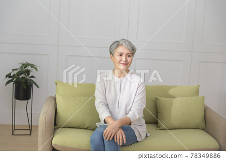 一位銀髮族年長婦女,坐在客廳的沙發上,享受悠閒自在的生活 78349886