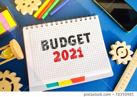 Notebook with inscription Budget 2021. Accumulating money and planning a budget. Business and finance. Loan, deposit, credit. Investments. Goals, income. Gears, hourglass, telephone Notebook with inscription Budget 2021. Accumulating money and planning a budget. Business and finance. Loan, deposit, credit. Investments. Goals, income. Gears, hourglass, telephone 78350485