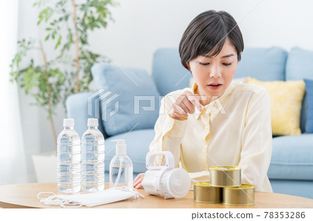 A woman checking the stockpile of disaster prevention supplies, evacuation supplies, and emergency food at home 78353286