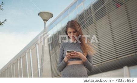 Portrait woman looking at smartphone while running outdoor. Close-up Of A Young Beautiful Sports Fitness Girl Holding A Smartphone In The Hands, Using A Fitness App. Modern City Shooting On the Street Portrait woman looking at smartphone while running outdoor. Close-up Of A Young Beautiful Sports Fitness Girl Holding A Smartphone In The Hands, Using A Fitness App. Modern City Shooting On the Street 78353699