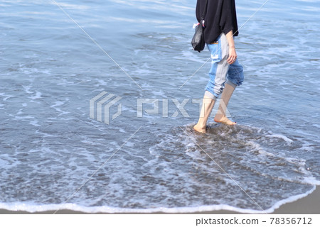 The feet of a woman walking along the beach 78356712
