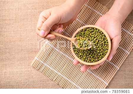 Mung bean seeds in spoon with bowl holding by hand Mung bean seeds in spoon with bowl holding by hand 78359081