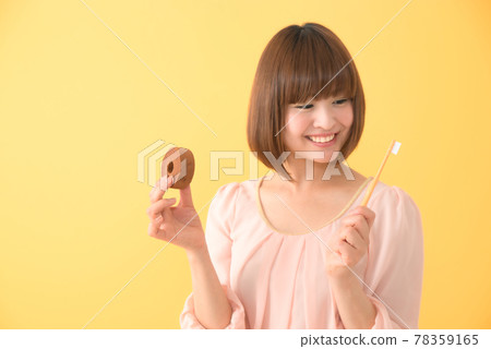 一個年輕女子微笑著，手裡拿著零食和牙刷 78359165