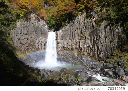 A rainbow appears in the Naena Waterfall basin of autumn leaves 78359959