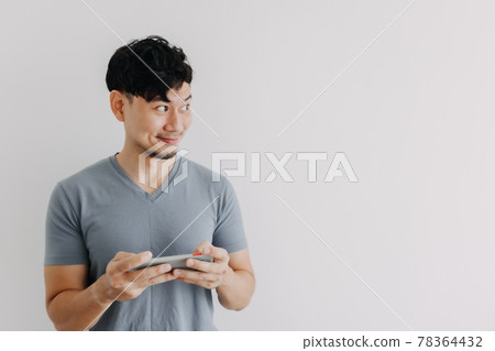 Happy man play online mobile game isolated on white background. 78364432