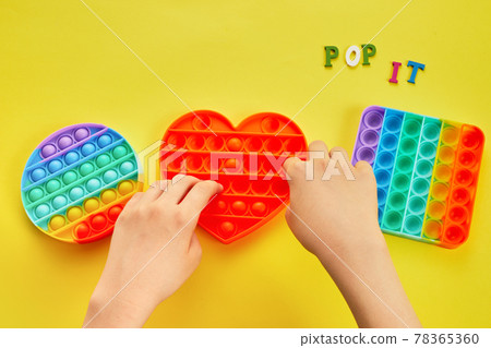 Kid hands playing with colorful pop It fidget toy. Colorful antistress sensory toy fidget push pop it. 78365360