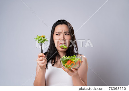 Asian woman trying to eat salad for diet isolated over white background. Asian woman trying to eat salad for diet isolated over white background. 78368230