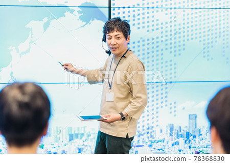 A male instructor who wears a headset and speaks enthusiastically at a workshop A male instructor who wears a headset and speaks enthusiastically at a workshop 78368830
