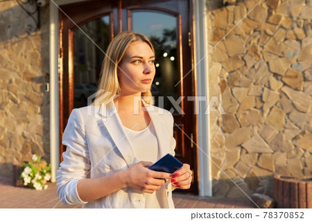 Portrait of young beautiful woman in white jacket, looking to side in sunset 78370852