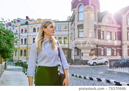 Outdoor young business woman with laptop bag walking along street Outdoor young business woman with laptop bag walking along street 78370986
