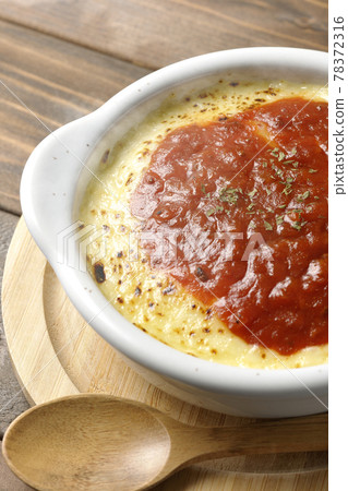 Hot doria, gratin and wooden spoon with plenty of melted and browned cheese placed on a pan Hot doria, gratin and wooden spoon with plenty of melted and browned cheese placed on a pan 78372316