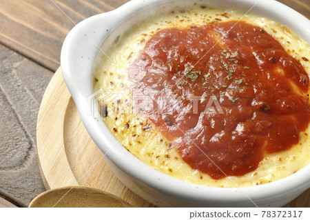 Hot doria, gratin and wooden spoon with plenty of melted and browned cheese placed on a pan 78372317