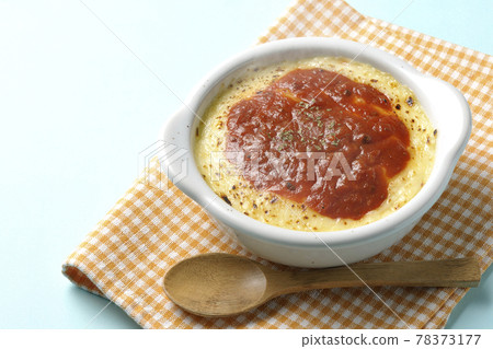 Doria, gratin and wooden spoon with plenty of melted and browned cheese in a place mat and bakeware 78373177