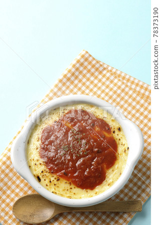 在餐墊、烤盤和木勺中的多利亞融化和褐色奶酪的鳥瞰圖。 在餐墊、烤盤和木勺中的多利亞融化和褐色奶酪的鳥瞰圖。 78373190