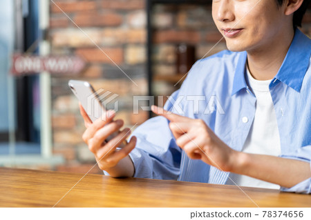 一個年輕人在咖啡館裡操作智能手機。 78374656