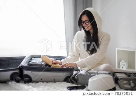 Focused woman making list packing suitcase organization. Clothes, cosmetic bag, case for equipment Focused woman making list packing suitcase organization. Clothes, cosmetic bag, case for equipment 78375051