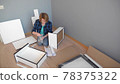 woman collects furniture while sitting on the floor at home, copy space 78375322