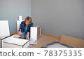 woman collects furniture while sitting on the floor at home, copy space 78375335