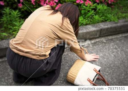 Image photo of a woman crouching when she feels sick Image photo of a woman crouching when she feels sick 78375531