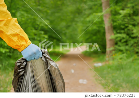 Volunteer cleaning up garbage a park. People care earth pollution plastic garbage worker hand holding trash bag. Volunteer hands picks up a plastic trash grass in park. Eco friendly background forest 78376225