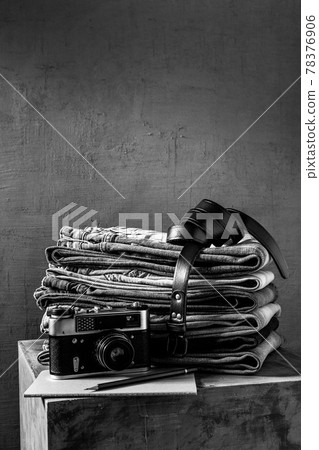 Denim jeans and leather belt at old grey cube near grey wall background.  Stack of jeans 78376906