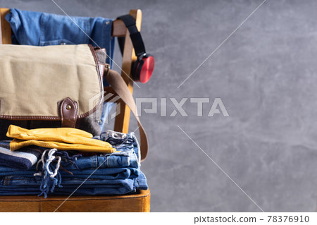 Denim jeans at old wooden chair grey and wall background texture.  Stack of jeans 78376910