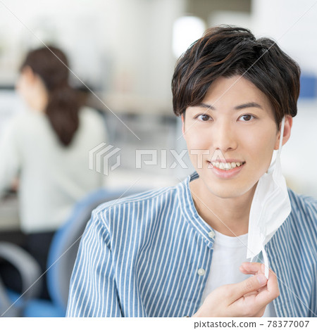 一位休閒風格的年輕商人,在辦公廣場上摘下面具微笑 一位休閒風格的年輕商人,在辦公廣場上摘下面具微笑 78377007