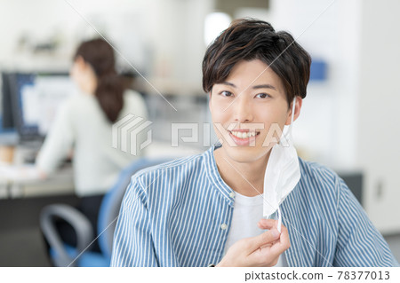 A casual-style young businessman who removes his mask and smiles in the office A casual-style young businessman who removes his mask and smiles in the office 78377013