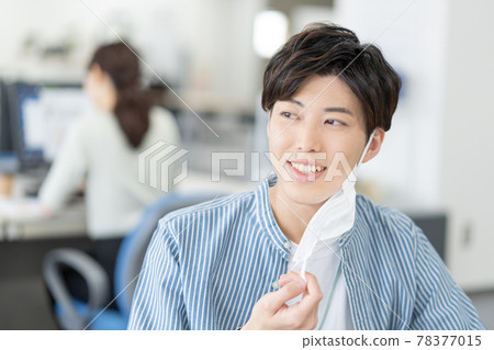 一個休閒風格的年輕商人,他在辦公室裡摘下面具微笑 一個休閒風格的年輕商人,他在辦公室裡摘下面具微笑 78377015